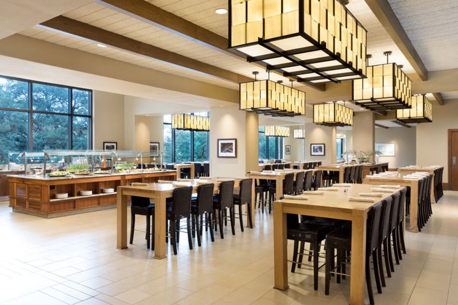 A large dining area with multiple tables and chairs, a buffet, and lighted ceiling fixtures.