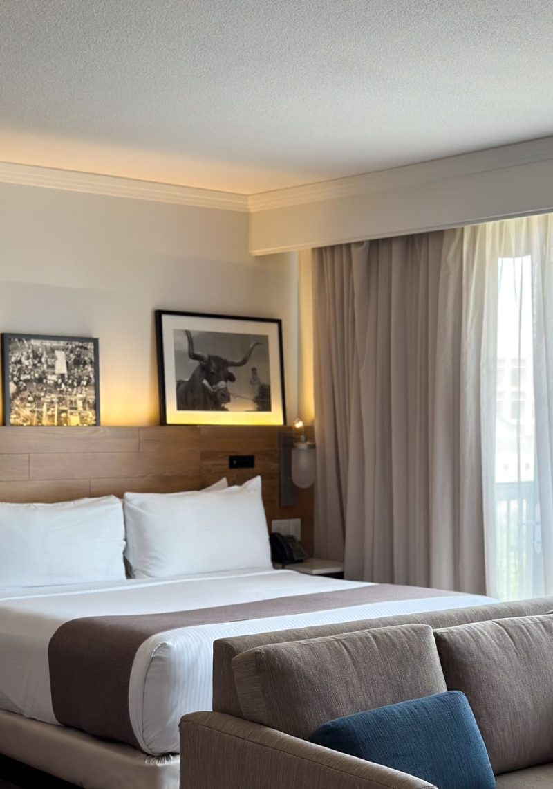 A hotel room with a large bed, a sofa, and a window with curtains.
