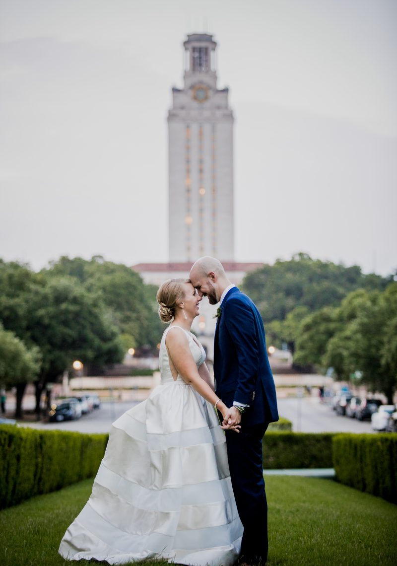 a couple in wedding attire in front of a tall building