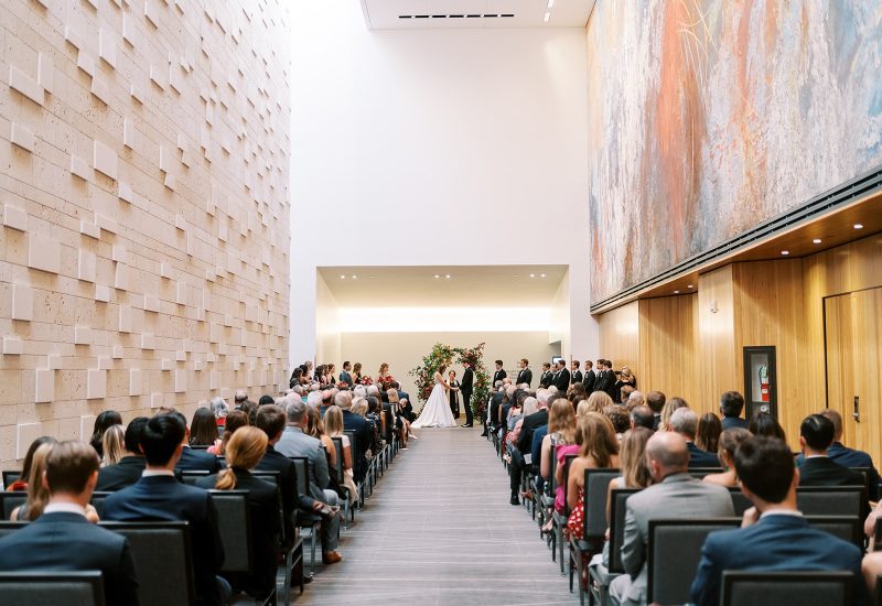 A large, high-ceilinged room with a wedding ceremony in progress.