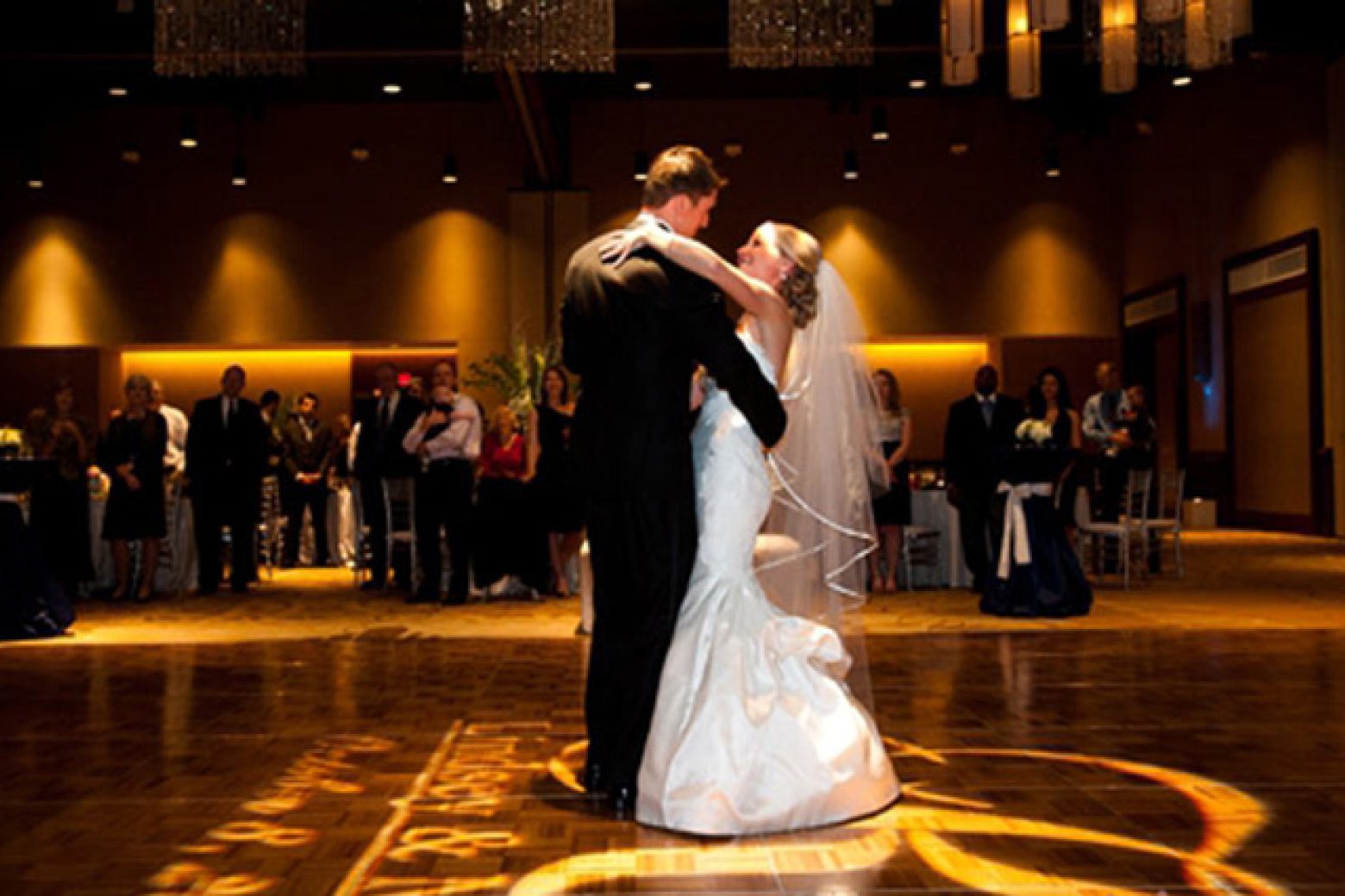A couple dancing in a large event space with a dance floor, tables, and chairs.