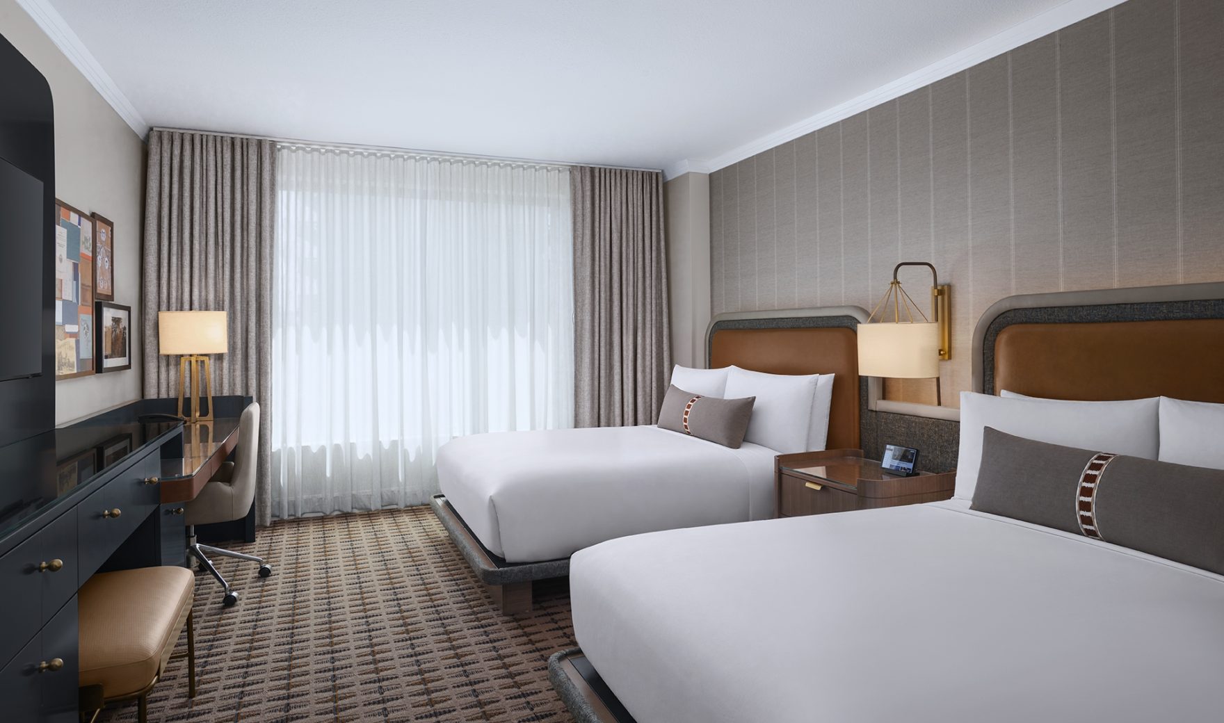 A hotel room with two beds, a desk, and a window