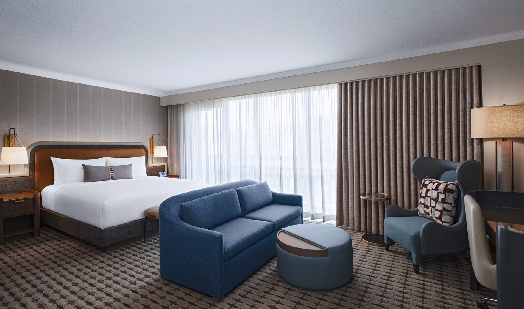 A hotel room with a bed, sofa, chair, and table.